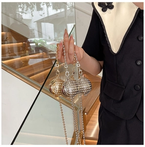 Detailed view of peanut-shaped evening clutch bag with white rhinestones and metal chain