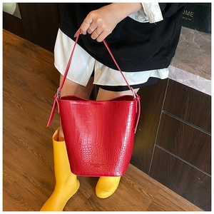 Detailed view of red crocodile-patterned bucket bag with leather texture and embossed text