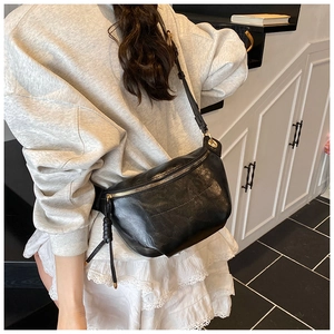 Detail showing high-quality black crescent bag worn as a crossbody with golden zipper