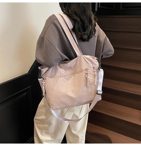 Detail of light pink nylon tote bag with adjustable shoulder strap and zipper pullers