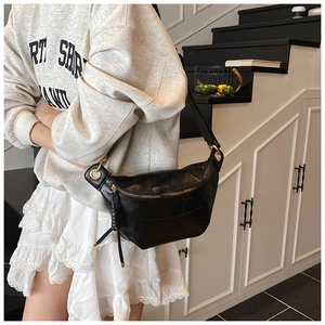 Close-up of black crescent crossbody bag featuring gold rings and tassel zipper detail