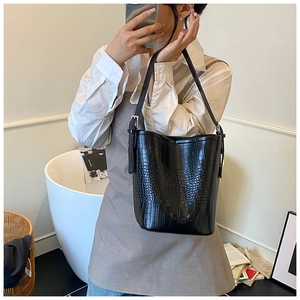Detail of black crocodile texture on a spacious bucket bag with adjustable strap