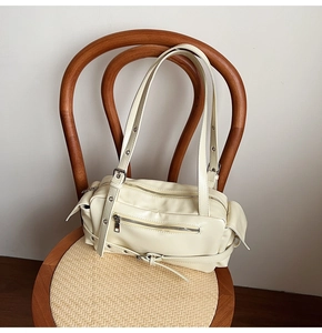 Détail du sac Boston crème avec fermetures éclair argentées et boucles à rivets