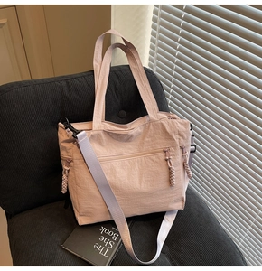 Close-up of pink tote bag with multiple zipper pockets and wide crossbody strap on a chair