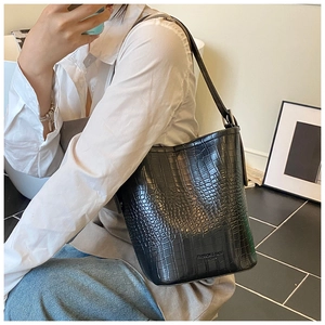 Detail of black crocodile texture bucket bag with adjustable shoulder strap and logo