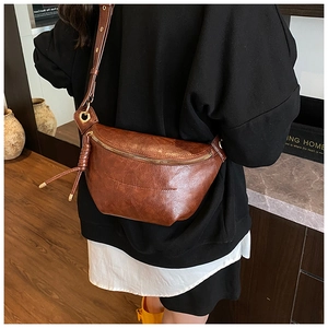 Detailed view of brown retro leather crossbody bag with golden zipper and fringe tassel