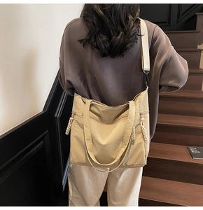Close-up of beige canvas tote bag with wide strap on a model at a staircase