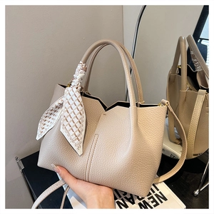 Detail of beige lychee leather tote with decorative scarf and gold hardware