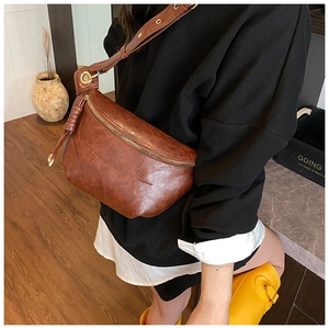 Close-up of retro brown half-moon chest bag with braided leather zipper and gold hardware