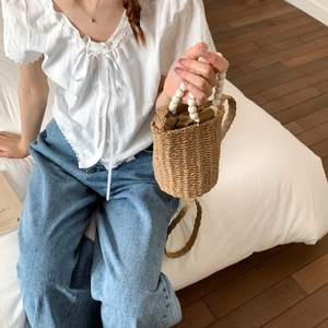 Mini straw bucket bag with white pearl ring handles and brown drawstring lining