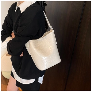 Detail of white crocodile pattern bucket bag with adjustable metal buckle strap