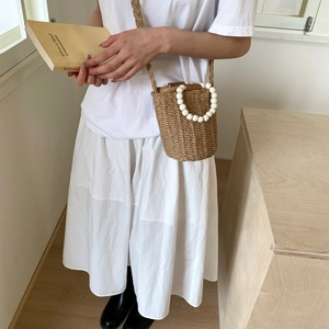 Handwoven straw bucket bag with large white bead handles for summer casual style