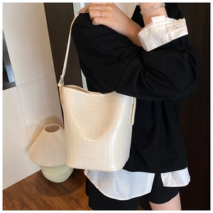 Detail of cream white bucket bag featuring elegant crocodile texture and fashion logo