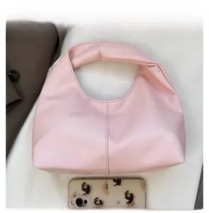 Detail view of pink pleated cloud bag comparing its compact size with a mobile phone
