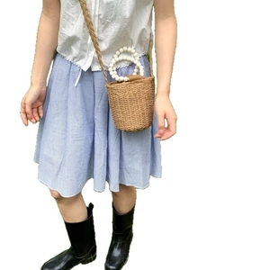 Trendy straw woven bucket bag with beaded handle and brown braided strap for summer