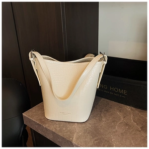 Detailed macro view of beige bucket bag with embossed crocodile texture and fashion logo