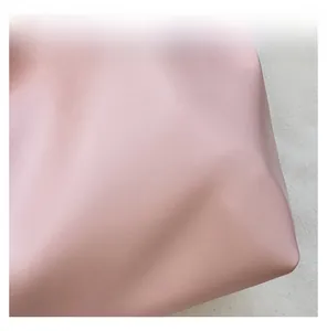 Close-up of pink leather underarm bag showing soft lychee grain texture and fine material
