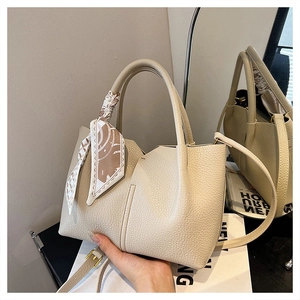 Detail of off-white lychee texture leather tote bag with stylish silk scarf handle