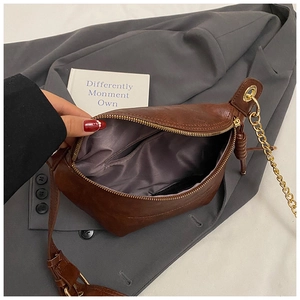 Detail view of the brown leather chest bag interior with grey lining and metal chain strap