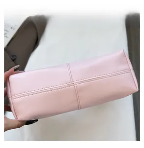 Detail shot of cross-stitch sewing and high-quality leather texture on light pink handbag