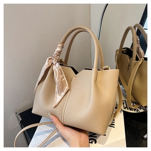 Detail of apricot pebbled leather tote with elegant geometric silk scarf on handle