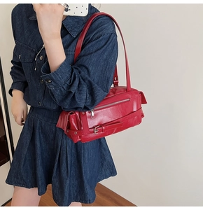 Détail du sac à épaule en cuir rouge avec fermetures éclair et rivets vintage