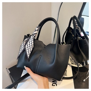 Detail of black lychee grain leather tote bag with a patterned silk scarf on handles