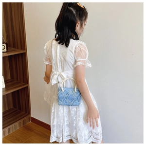 Détail du sac à bandoulière en denim bleu avec texture losange effilochée et chaîne