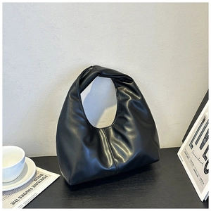Detail of minimalist black hobo bag with soft faux leather texture and folded handle