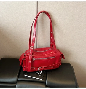 Détails du sac moto rouge avec rivets argentés et finition brillante en cuir huilé