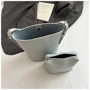 Detail of light blue crocodile texture bucket bag set with inner zip pouch on fabric