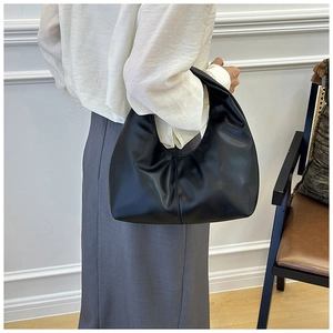 Model showing a black ruched cloud hobo bag on the arm with a white shirt and grey skirt