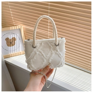 Détail du sac bandoulière en toile blanche avec motif losanges effilochés et chaîne à perles