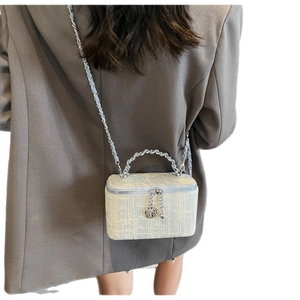 Blue and beige tweed box bag with chain strap and rose charm shown on a model