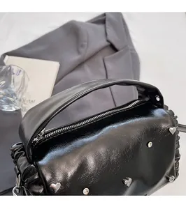 Detail of glossy black leather handbag featuring silver heart studs and sparkling rhinestones