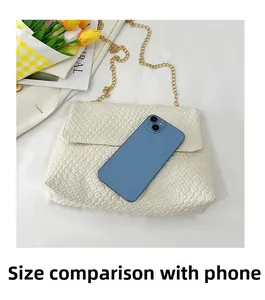 Detailed view of woven leather tote bag with gold chain next to smartphone for scale