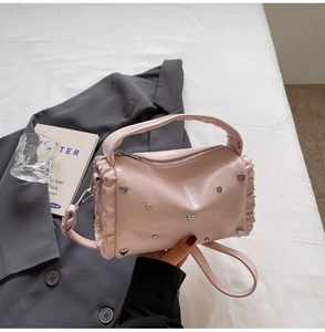Detail of pink cylindrical leather handbag with silver heart studs and ruched side design