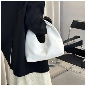 Detailed view of a white half-moon shoulder bag with sleek pleats and top handle design