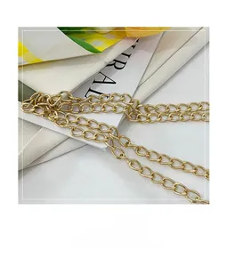 Detailed view of the bright gold metal chain strap on a white textured fabric background