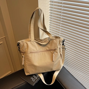 Minimalist beige nylon tote bag with functional zipper pockets and woven rope zipper pulls