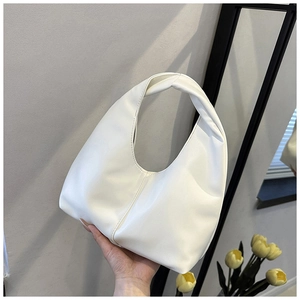 Detail of a minimalist white leather half-moon hobo bag held by a person