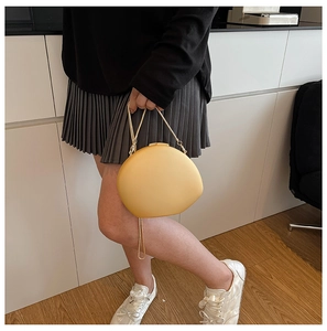 Detail of yellow oval evening bag featuring a sleek golden chain handle and matte finish