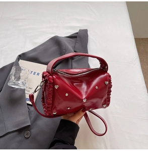 Detail of red glossy handbag with silver heart studs and ruffled edge side design