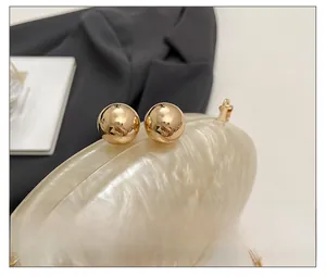 Detailed close-up of pearl white marble acrylic clutch with elegant golden sphere clasp