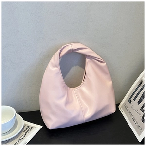 Minimalist pink underarm bag with twisted handle detail in a lifestyle setting