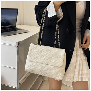 Detailed view of white woven texture shoulder bag with golden metal chain strap