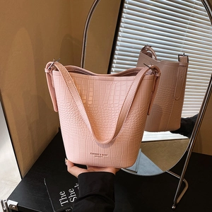 Light pink crocodile pattern bucket bag with adjustable strap and fashion logo