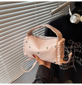Pink Boston bag with ruffled edges and silver heart stud details in a hand-held view