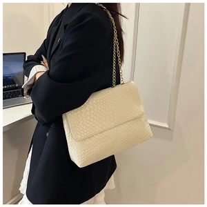 Detail of cream white faux snakeskin shoulder bag with elegant gold chain strap