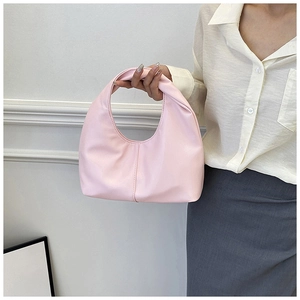 Detail of light pink crescent underarm bag in soft PU leather held by a model